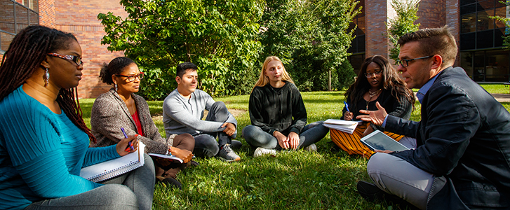 Professor having discussion with class in group circle outside